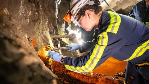 A researcher collects a water and microbial sample underground 