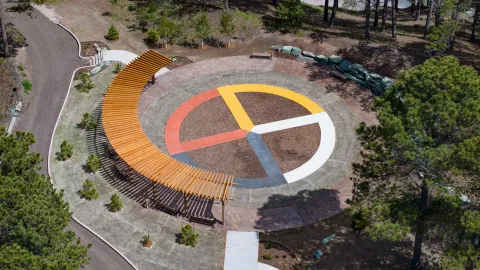 An aerial drone shot of SURF's ethnobotanical garden, Čhaŋgléška Wakȟáŋ, showing the colors of the medicine wheel, a Lakota inspired pergola, and the access road and paths.  