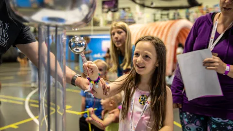 A child takes part a science learning activity utilizing a Van De Graaff generator brought to Neutrino Day 2024 by South Dakota Mines. 
