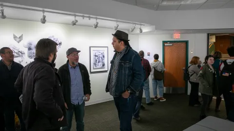 People speak with Marty Two Bulls at the artist reception in the Ruddell Gallery