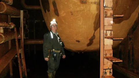 Tom Regan poses underground in PPE near a large tank