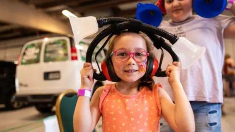 A child enjoys a hands-on learning exhibit with Little Shop of Physics at Neutrino Day 2024 