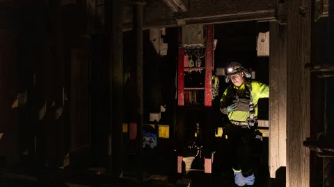 Will Hover stands on a platform inside the Yates shaft, surrounded by timbers and the darkness.