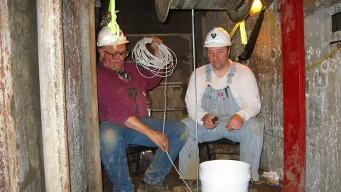 Dan Regan and Greg King lowering a camera into a shaft for an inspection at SURF. 