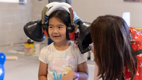 Children engage in hands-on learning fun with a listening contraption built by the Little Shop of Physics during Neutrino Day 2025.  