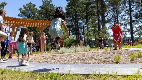 A child jumps through a hoop at Čhaŋgléška Wakȟáŋ during the 2025 celebration of Neutrino Day. 