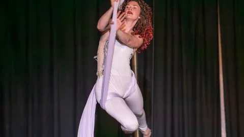 An aerialist swings on silks