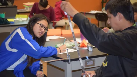 A pair of students consider balanced and unbalanced forces in a counter balanced system.