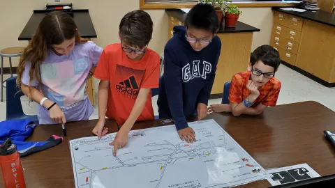 A team of students examine a map of an underground excavation.