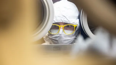 A researcher works inside a glove box on experiment components. 