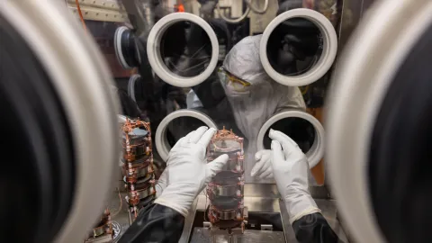 A researcher works inside a glove box on experiment components. 