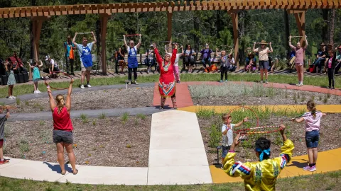 A group of people learning the basics of hoop dancing at the garden at SURF.